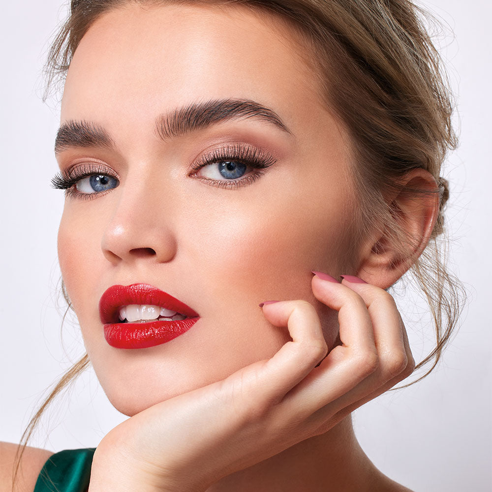 Model mit rot geschminkten Lippen trägt die neuen nachfüllbaren Wimperntuschen aus der Refillable Mascaras-Kollektion