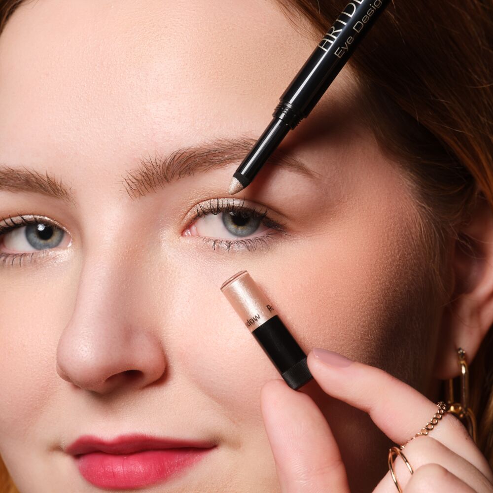 Frau mit roten Haaren veranschaulicht die Anwendung des Eye Designer mit der dazugehörigen Refill-Patrone an ihrem Auge