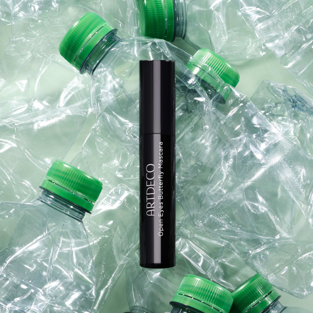 Mascara liegt auf einem Untergrund umgeben von leeren Plastikflaschen