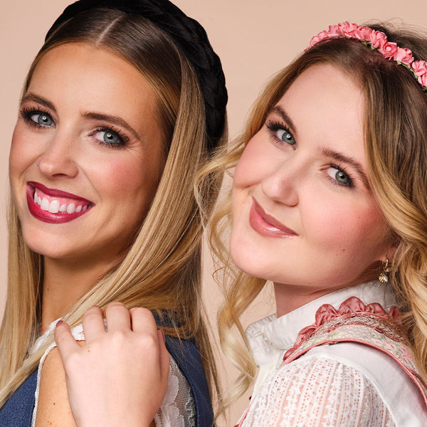 Beide Models mit ihren Oktoberfest-Make-ups stehen seitlich und lächeln freundlich in die Kamera