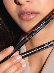 Die zwei Farben des Sculpting Brow Styler werden vor das Gesicht des Models gehalten.