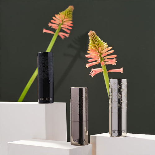 Inszenierung der drei Couture Lipstick Cases auf weißen Podesten mit Blumen im Hintergrund