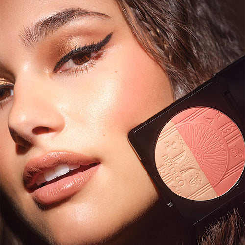 Close-up auf das Gesicht des Models, welche den limitierten Blush Luminizer„devine glow“ an ihre Wange hält und somit den Effekt des Produktes zeigt.