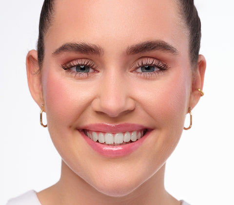 Nachherbild des Clean Girl Make-Up Looks. natürlich geschminktes und lächelndes Model mit strengen Zopf.