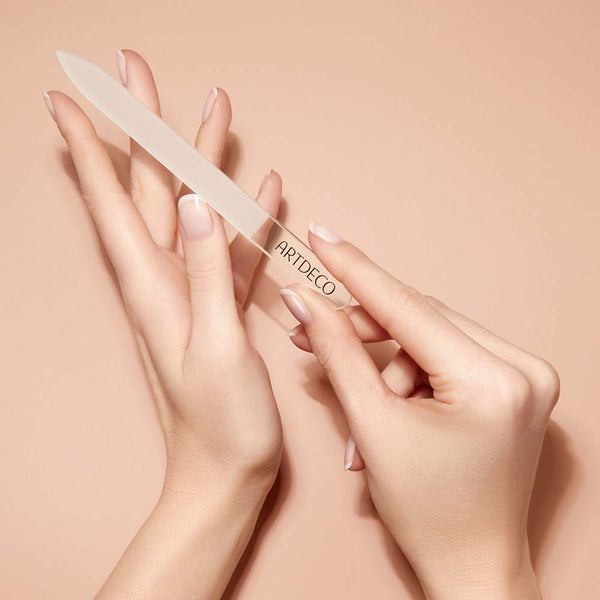 Eine Glasnagelfeile wird elegant in den Händen gehalten.