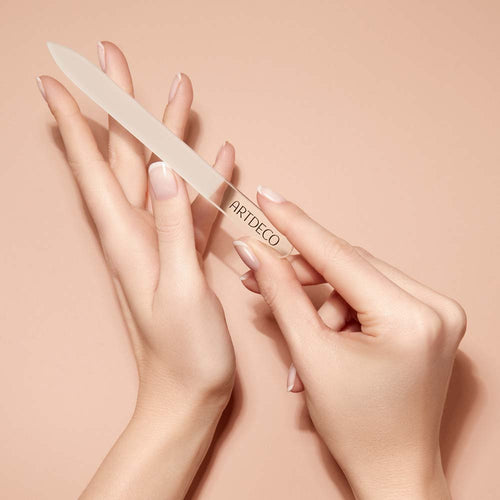 Eine Glasnagelfeile wird elegant in den Händen gehalten.