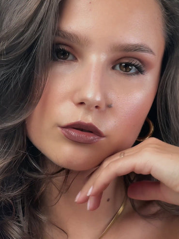 Model mit fertig geschminktem Latte Make-Up hält ihre Hand elegant ans Gesicht.