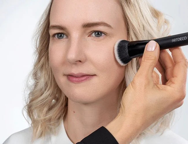 Das Make-up wird mit einem Fixing Puder mittels eines Pinsels eingeblendet