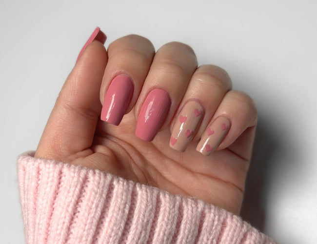 Auf die Nägel des Zeigefingers und des kleinen Fingers werden mithilfe eines Dotting Tools und einen dünnen Pinsels Herzen gezeichnet.