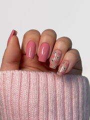 Nageldesign für Valentinstag mit rosa Herzen und glitzernden Steinchen.