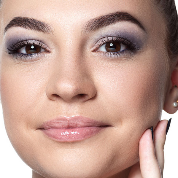 Ein geschminktes Model schaut in die Kamera und lächelt.