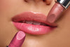 Es werden zwei Lippenstifte mit unterschiedlichen Farbnuancen vor geschminkten Lippen gehalten