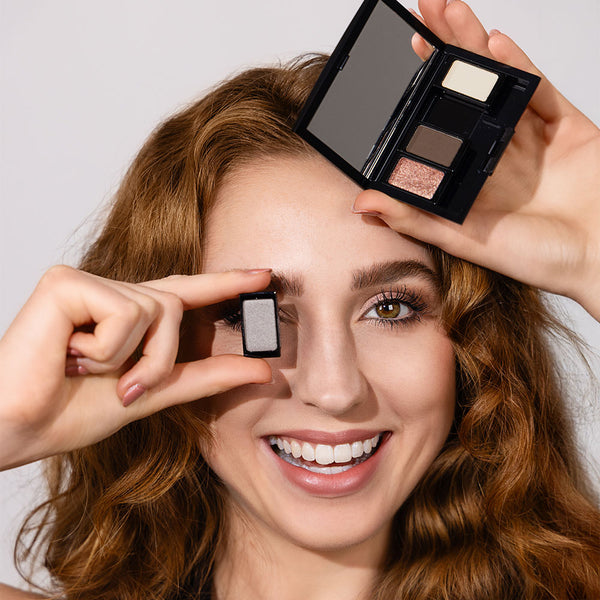 Model mit rötlichen Haaren hält Beauty Biox mit dazugehörigen Lidschatten aus der 40 Jahre ARTDECO-Kollektion in der Hand und lächelt dabei
