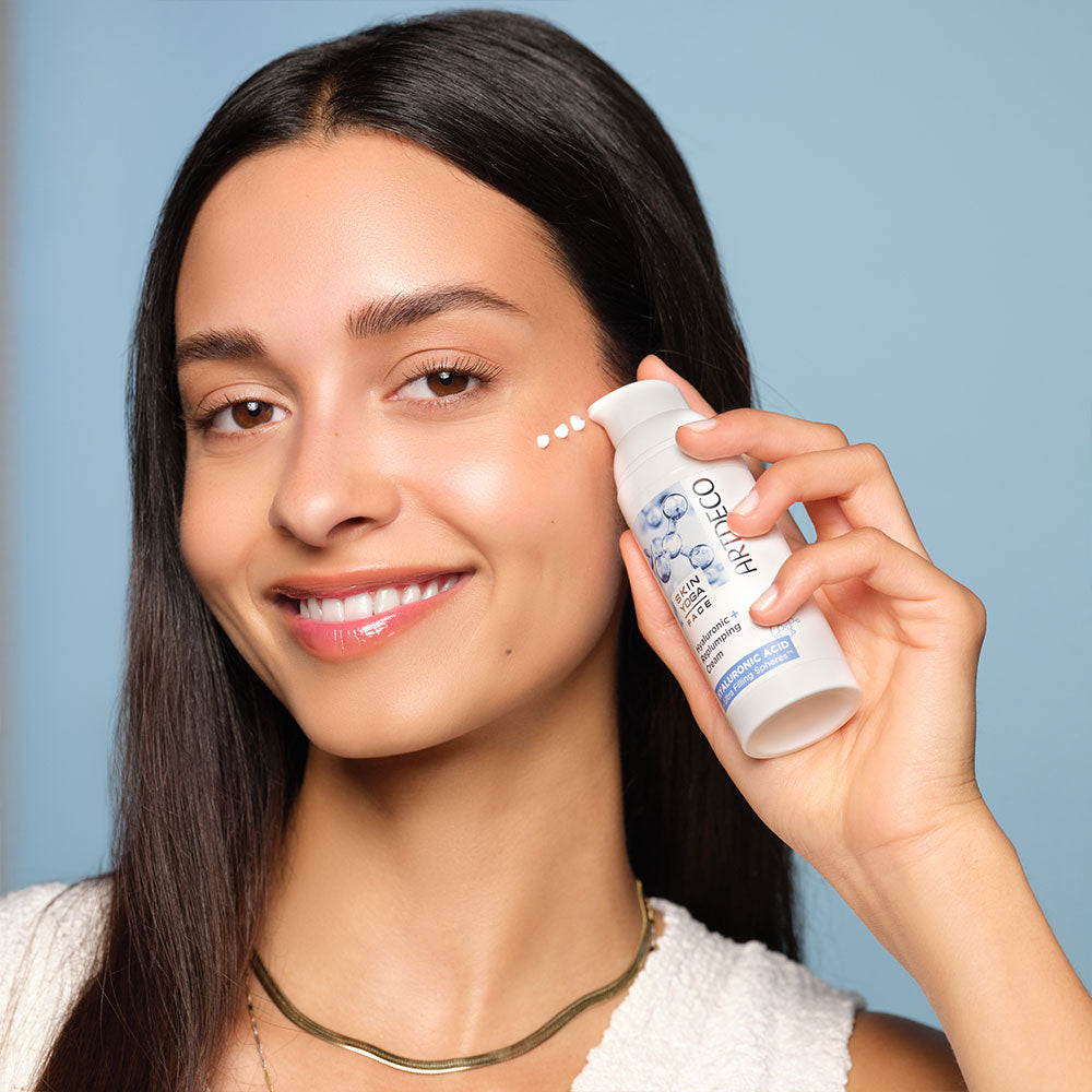 Brünettes Model trägt die Hyaluronic + Replumping Cream punktuell auf ihre Wange auf.