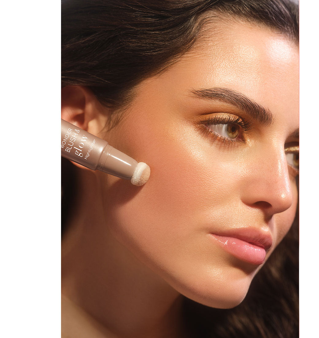 Brünettes Model mit glowy Make-up trägt den Wonder Blush & Glow Highlighter mit dem Schwämmchenapplikator auf ihre Wange auf, und dieses Ergebnis zu erzielen