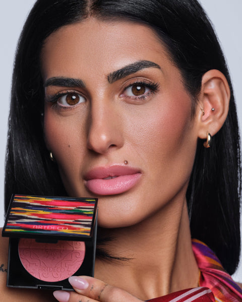 Model steht front zur Kamera und hält den halb geöffneten Blush Couture in einer Hand.