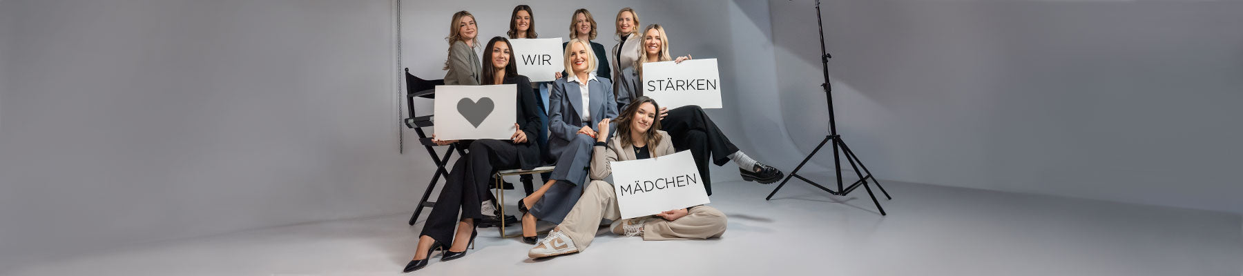 Acht Frauen von ARTDECO die weißen Schilder mit dem Satz „Wir stärken Mädchen“ hochhalten