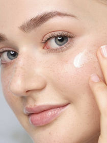  Hyaluronic Intensive Serum wird mit den Fingern auf die Wange eines Models aufgetragen