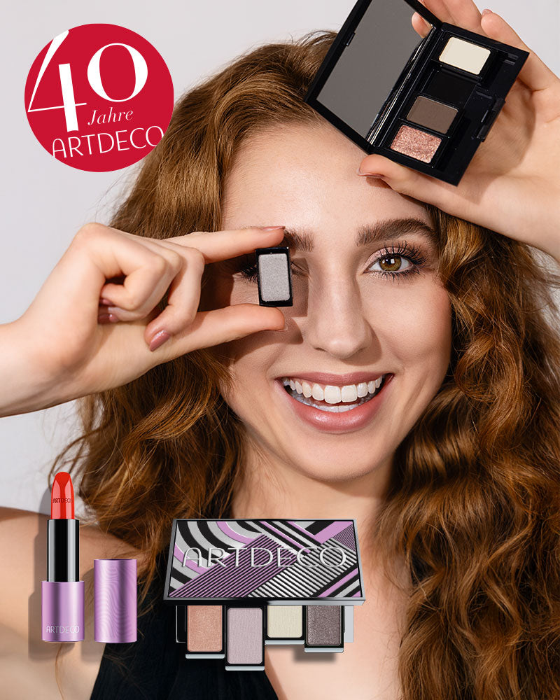 Model mit rötlichen Haaren hält eine Beauty Box Quattro mit ausgewählten Lidschatten in der Hand und lächelt. Daneben grafisch abgebliegt sind weitere Produkte der 40 Jahre ARTDECO-Kollektion, wieso ein Störer auf welchem "40 Jahre ARTDECO" steht