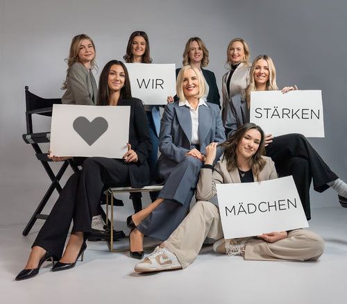 Acht Frauen von ARTDECO die weißen Schilder mit dem Satz „Wir stärken Mädchen“ hochhalten