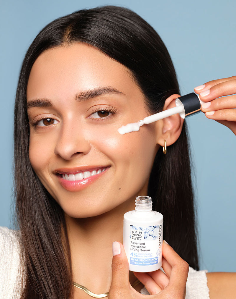 Brünettes Model trägt das Advanaced Hyaluronic Lifting Serum mit einer Pipette auf ihre Wange auf. Das Produkt ist Teil der Super Skin Replump-Pflegelinie mit 3-fachen Hyaluronkomplexen