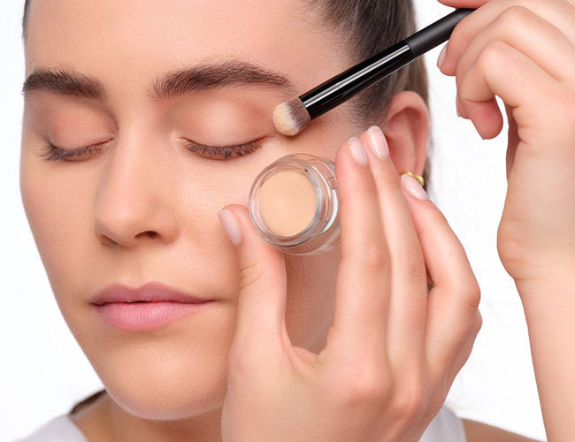 Model trägt cremigen ARTDECO All in One Eye Primer​ mit dem Concealer & Camouflage Brush​ auf das Augenlid auf.