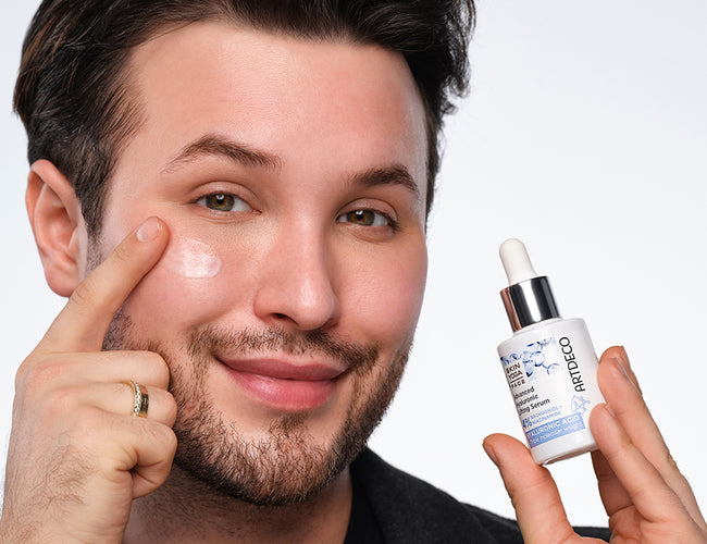 Männliches Model trägt das Advanced Hyaluronic Lifting Serum auf die Wange auf.
