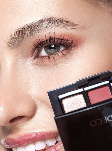 Frau hält Beauty Box mit zwei Lidschatten die in dem Schminktipp verwendet wurden an ihr Auge