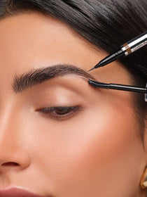 Model definiert die Augenbrauen mit einem filigranen Augenbrauenstift und kämmt die Härchen mit einem schmalen Bürstchen für ein präzises Abend-Make-up.