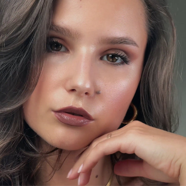 Model mit herbstlichen Latte Make Up Look hält elegant ihre Hand ans Gesicht.
