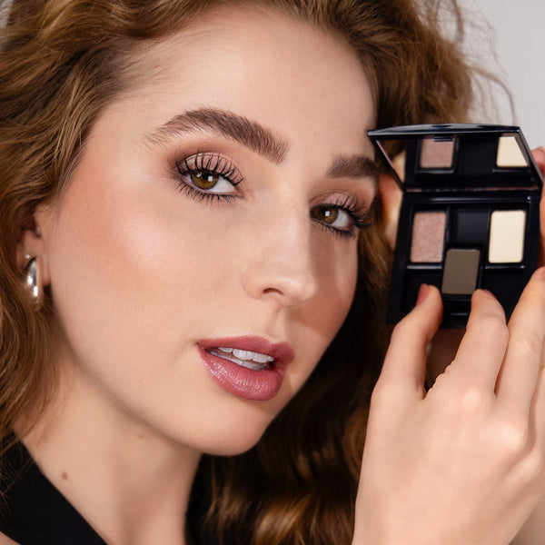 Model mit rötlichen Haaren hält eine Beauty Box Trio mit ausgewählten Lidschatten in der Hand für das perfekte Make-Up für braue Augen.