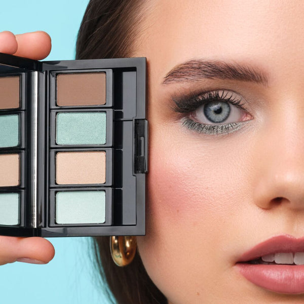 Model mit blauen Augen hält eine Beauty Box Quattro mit passenden Lidschatten für blaue Augen nah an ihre Augen.