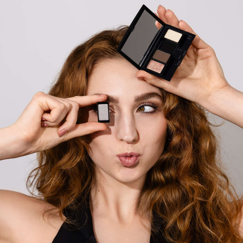 Frau mit roten Haaren und Kussmund hält eine befüllbare magnetische Palette und passenden Lidschatten von Artdeco am Gesicht.
