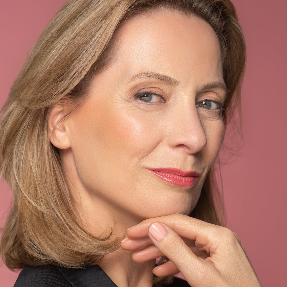 Geschminktes älteres Model hält elegant ihre Hand ans Gesicht.