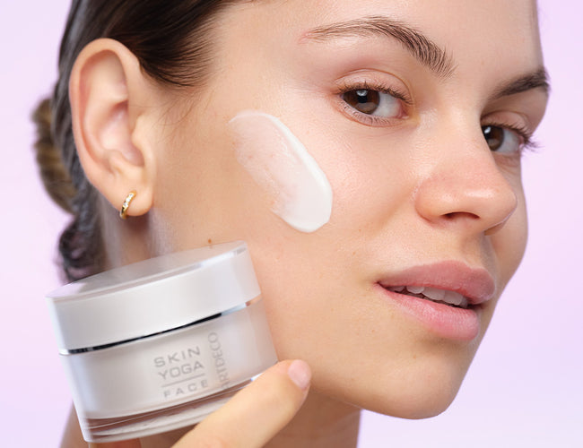 Das Model ist im Profil zu sehen und hat einen Produkt-Swatch ihrer Gesichtscreme auf der Wange 