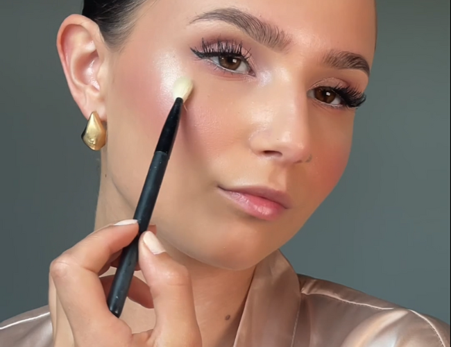 Der Highlighter wird mit einem kleinen Pinsel auf die oberen Wangen aufgetragen.