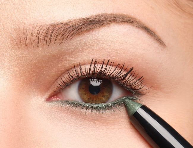 Grüner Eyeshadow Stick wird auf die untere Wasserlinie aufgetragen. 