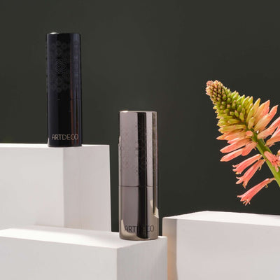 Nachfüllbare Verpackungen des Cotour Lipsticks auf verschieden hohen Podesten und einer Blume im Hintergrund. 
